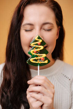 Young woman face close-up with sweet fir lollipop for new year. Christmas traditional holiday.の写真素材