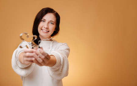 Smiling young woman on a yellow background holds metal forms for Christmas gingerbread.の写真素材