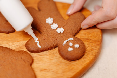 Christmas gingerbread cookies in the form of a man are decorated with white glaze on a wooden board. Confectionery concept.の写真素材