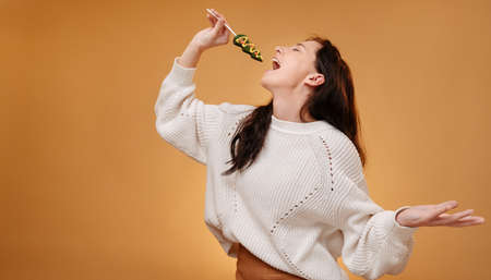 Young woman in a white sweater sings into a microphone of sweet candy in the form of a Christmas tree.の写真素材
