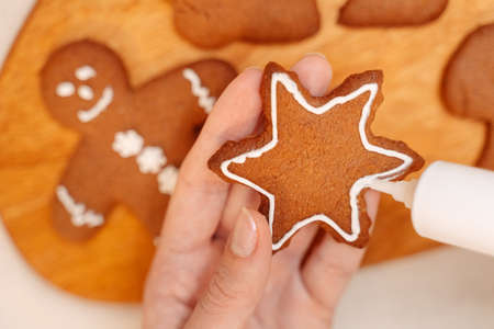Decorate freshly baked snowflake cookies with white sweet mastic from a tube. Christmas sweet food concept.の写真素材