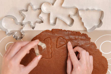 Gingerbread dough with different shapes of metal cutters for Christmas family cookies with ginger...