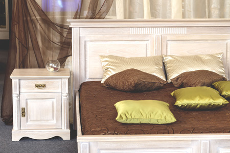 light bedside table near bed with brown pillows on the bed