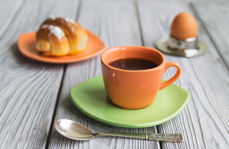 breakfast an egg of a coffee croissant on a wooden backgroundの写真素材