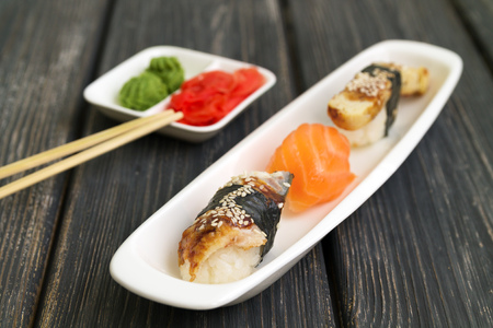 japanese cuisine, sashimi cooked on a white plate close-up, on a dark wooden background, ginger and wasabi wooden sticksの写真素材