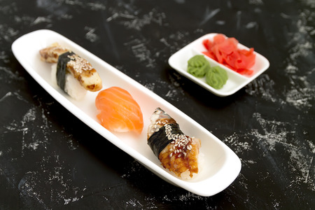 Japanese sushi sushimi on a white plate close-up, on a black background with ginger and wassabiの写真素材