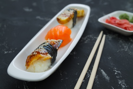Japanese sushi sushimi on a white plate close-up, on a black background with ginger and wassabiの写真素材