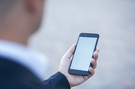 Touch screen of a mobile phone, in the hand of a businessman. Photo for Mock Up.の写真素材