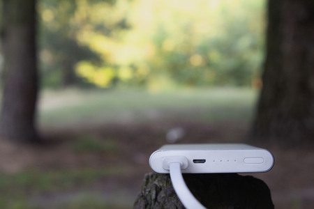 Portable charger. Power Bank with cable against the background of nature and wood.の写真素材