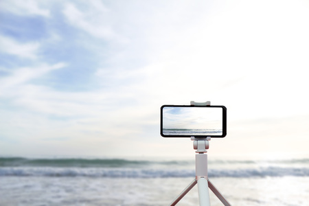 Mobile shooting on a journey. Smartphone on a tripod on the background of the sea in Spain in Palma de Mallorca.の写真素材