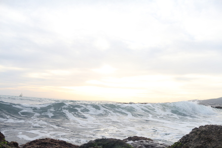 Sunset on the background of the sea and reefs with a small ship in the distance on island Palma de...