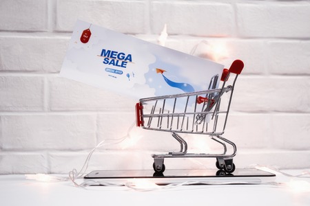 Online sale concept. Shopping cart and flyer with glowing lights on the tablet and on the background of a brick wallの写真素材