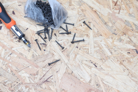 Screwdriver with black screws on the background of the OSB panel. Concept on the topic of building and repair.の写真素材