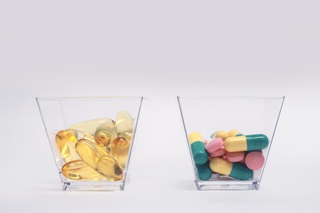 Fish oil capsules and tablets in glass cupsの写真素材