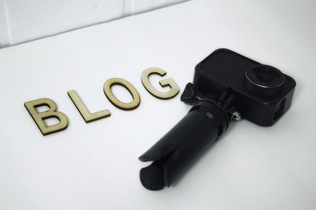 Concept on the topic of Blogger. Action Camera with wooden letters on a white backgroundの写真素材