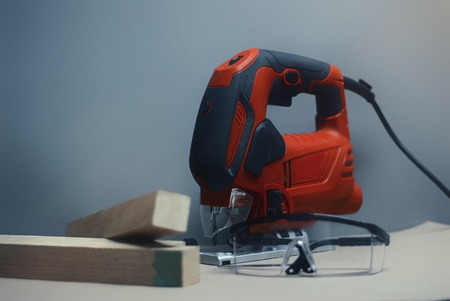 Electric jig saw machine on the background gray wall.