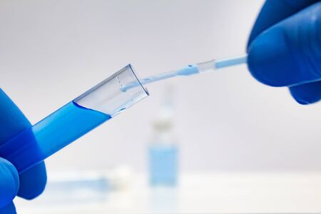 Scientist hand holding laboratory test tube and conducts scientific research on light background.