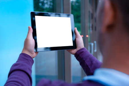 Mockup image of a Man holding black tablet in hand with blank white screen on background in the doorの写真素材