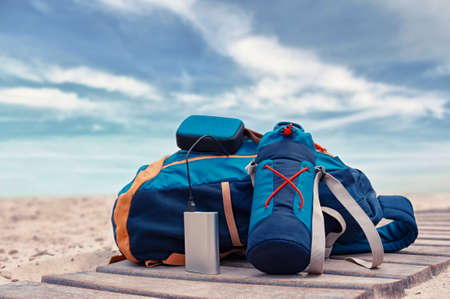 Portable travel charger. Power Bank charges a musical speaker against a backdrop of journey bags, a...