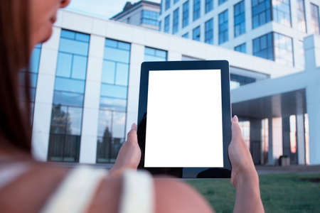 Young woman demonstrates the screen white screen tablet close-up. Mock up on the background of a modern business centerの写真素材