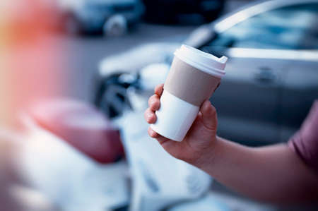 Man holds an ecological cup with coffee in his hand. Mock up paper cup on the background of a...