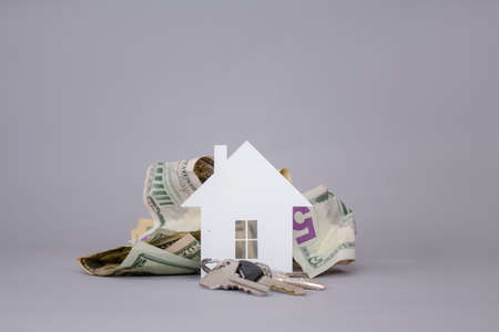 Dollars and home keys on a gray background. Money set aside to buy a House.