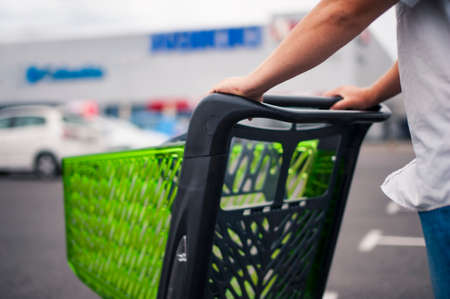 Man with a supermarket trolley in the parking lot against the background of the car.の写真素材