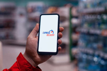Express delivery in your phone. A man holds a smartphone with an icon on a white screen in his...