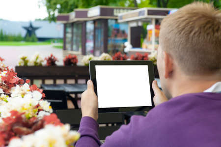 Mockup image of a Man holding black tablet in hand with blank white screen on background in cafeの写真素材