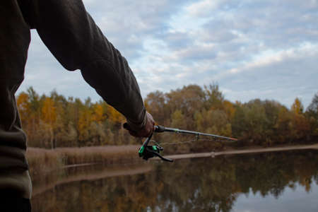 Man fisherman catches a fish on a fishing rod with a reel on the lake against the background of the...