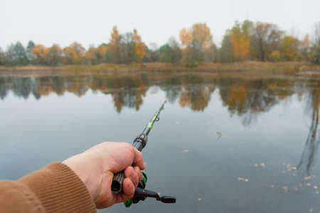 Man fisherman catches a fish on a fishing rod with a reel on the lake against the background of the...