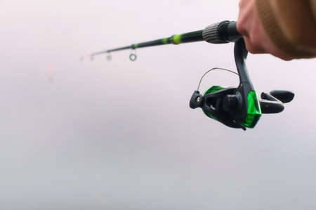 Man fisherman catches a fish on a fishing rod with a reel on the lake