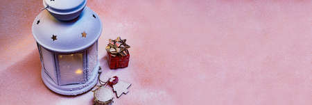 Festive concept for Christmas and New Year. A beautiful decorative lamp glows on a snowy background with gift boxes, drums and a wooden Christmas treeの写真素材