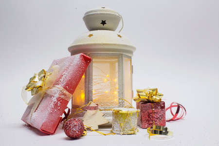 Christmas and New Year composition. Festive glowing lantern with decorations, gifts and bright bows...