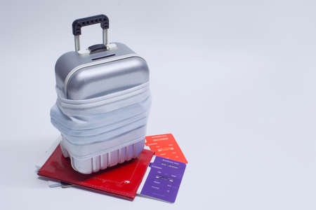 Time to travel. The concept of safe rest during a pandemic Covid-19 Coronavirus. Suitcase for travel with a medical mask and plane tickets with a passportの写真素材