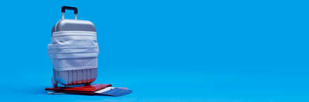 Time to travel. Flight cancellation and safe rest concept during a pandemic Covid-19 Coronavirus. Suitcase for travel with a medical mask and plane tickets with a passportの写真素材