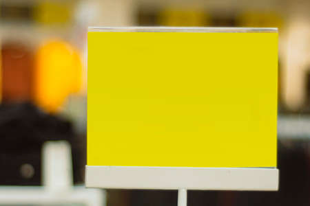Yellow paper mockup of a discount signboard on the background of a store with clothesの写真素材