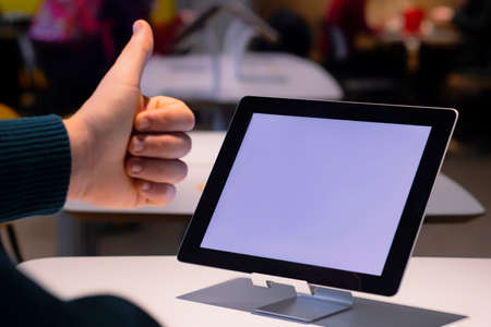 Mock-up Technology. Businessman shows thumbs up on the background of a digital tablet with white screenの写真素材