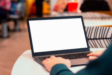 Close-up laptop mockup with white screen. A male freelancer works in a cafe