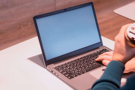 Close-up laptop mockup with white screen. A male freelancer works in a cafeの写真素材
