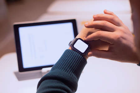 Businessman with digital tablet with white screen on the table and smart watch on his hand. A male freelancer works in a cafeの写真素材