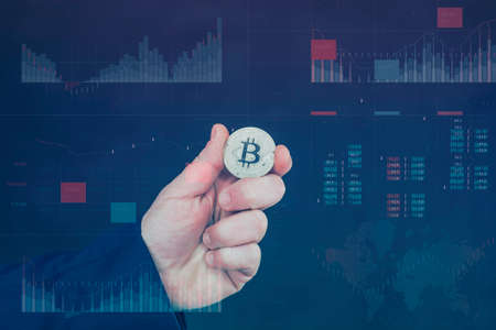 Businessman holds a gold bitcoin coin in his hands. Information holographic panel with statistics...