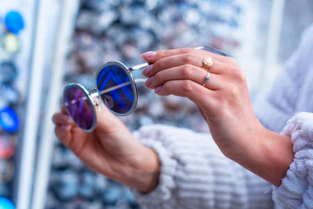 A woman chooses protective sunglasses against the background of a showcase with glassesの写真素材
