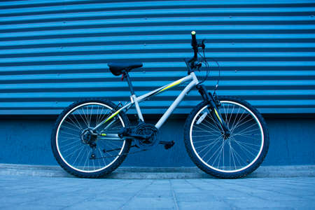 A mountain bike stands on the paving slabs against the background of a gray wallの写真素材