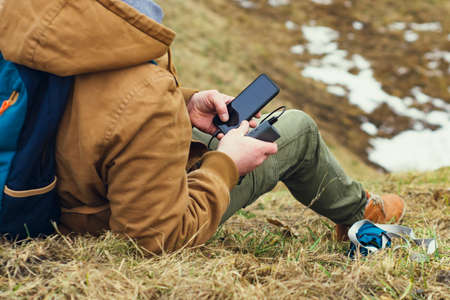 Tourist is holding a portable charger with a smartphone in his hand. Man on a background of nature...
