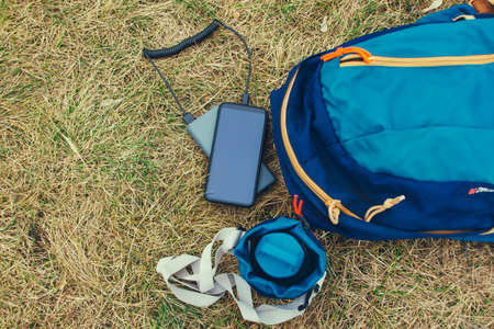 Smartphone is charged using a portable charger. Power Bank charges the phone outdoors with a backpack for tourism in nature.の写真素材