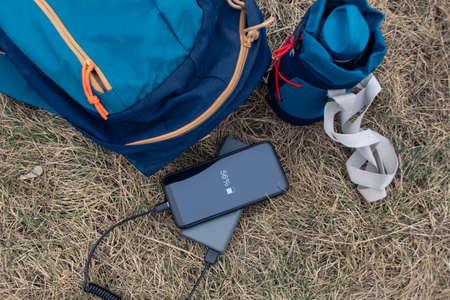 Smartphone is charged using a portable charger. Power Bank charges the phone outdoors with a backpack for tourism in natureの写真素材