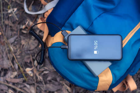 Smartphone is charged using a portable charger. Power Bank charges the phone outdoors with a...