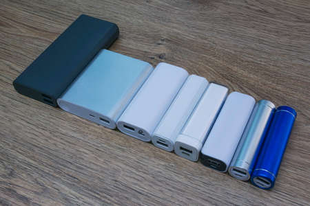 Choosing a portable charger. Set of power banks of different sizes on a wooden table