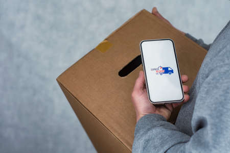 Express delivery in your phone. A man holds a smartphone with an icon on a white screen in his handsの写真素材